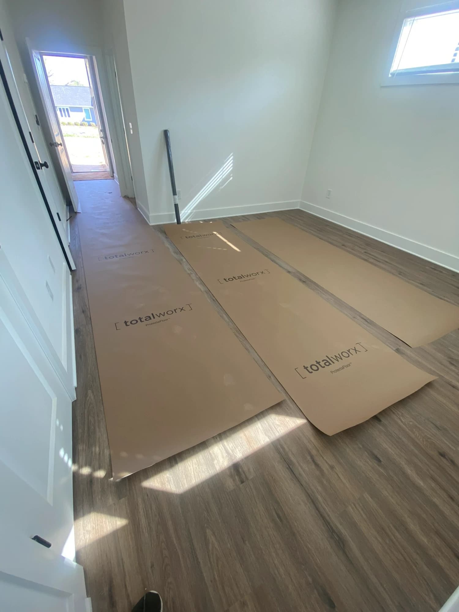 Finished rigid-core luxury vinyl plank floor covered with kraft protection paper on a Charlotte job site