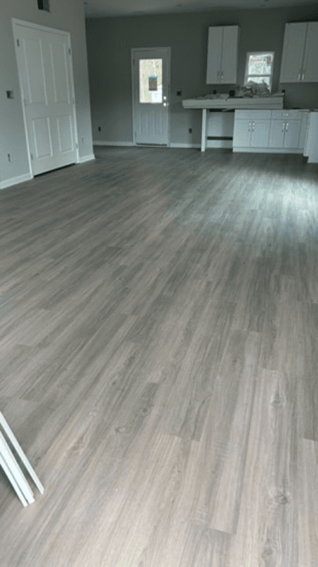 Grey oak luxury vinyl plank across an open-concept living room and kitchen